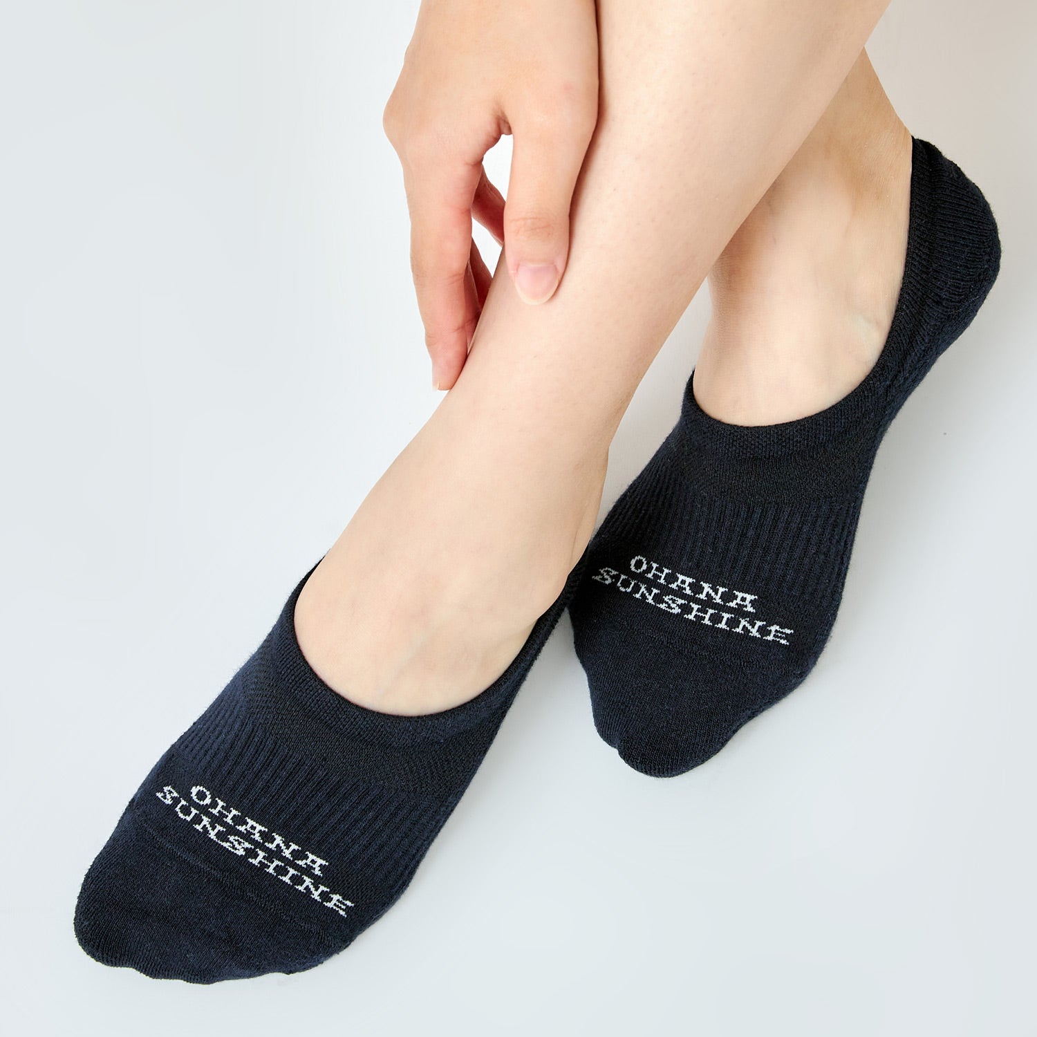 Model wearing black no-show socks with “Ohana Sunshine” logo, showing low-cut design and snug fit over the foot