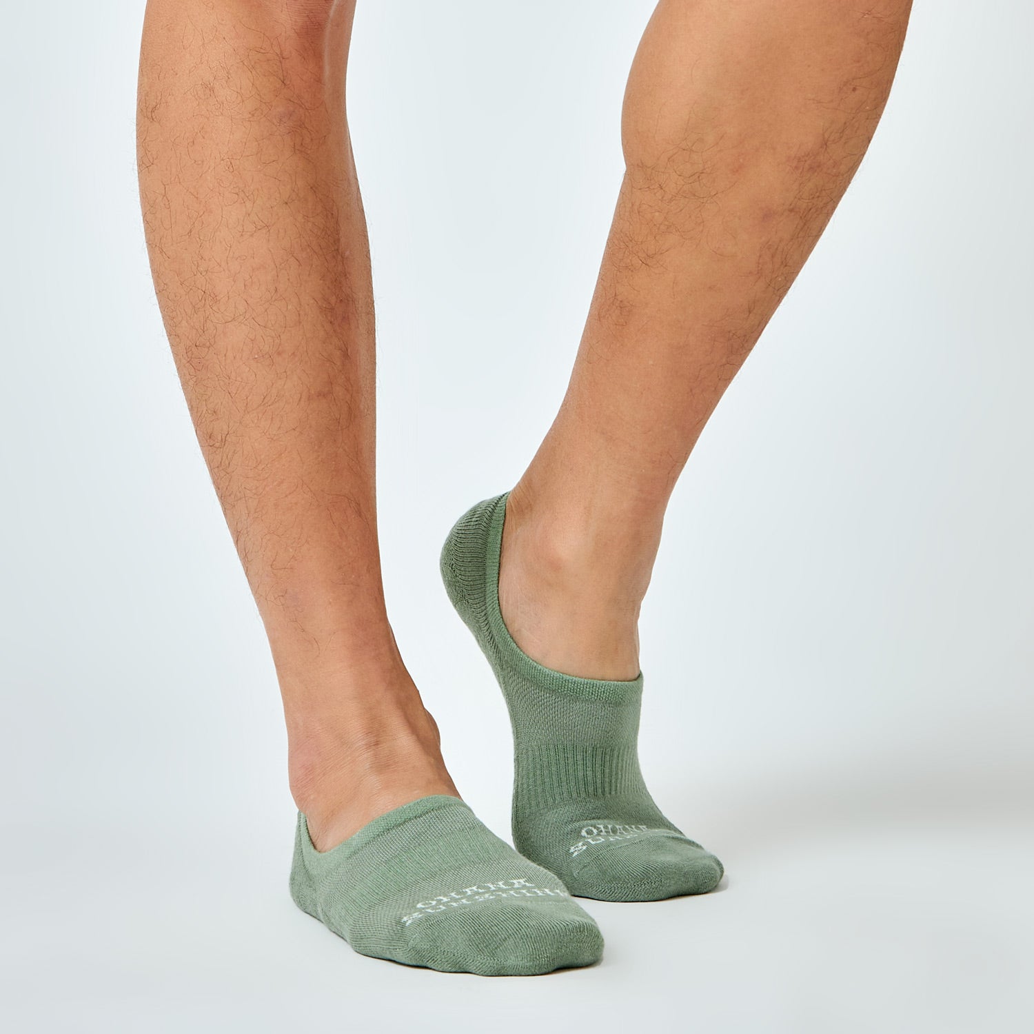 Male model wearing black no-show socks with “Ohana Sunshine” logo, showing low-cut design and snug fit over the foot