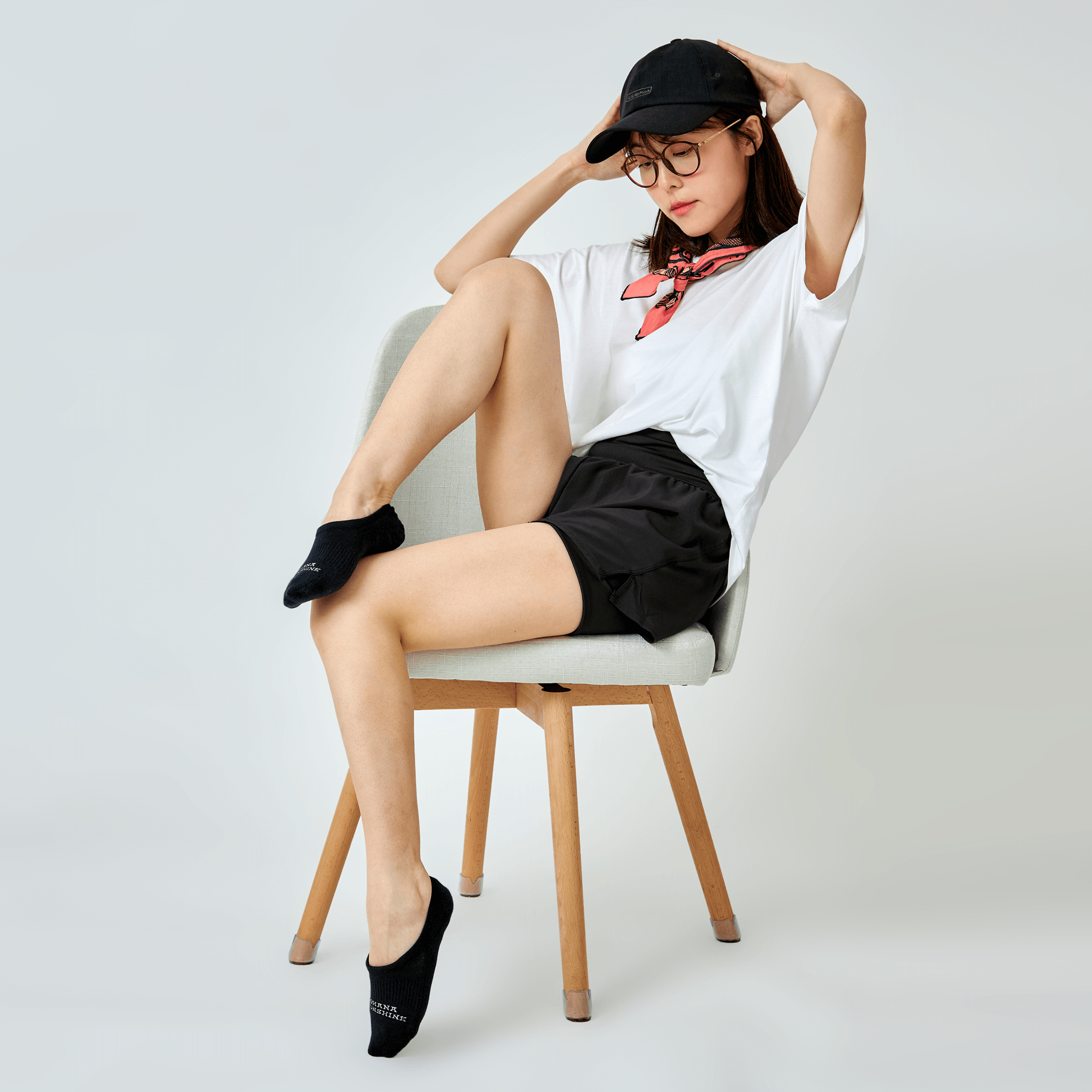 Model seated in casual outfit wearing black no-show socks with Ohana Sunshine logo, showcasing relaxed everyday style and fit