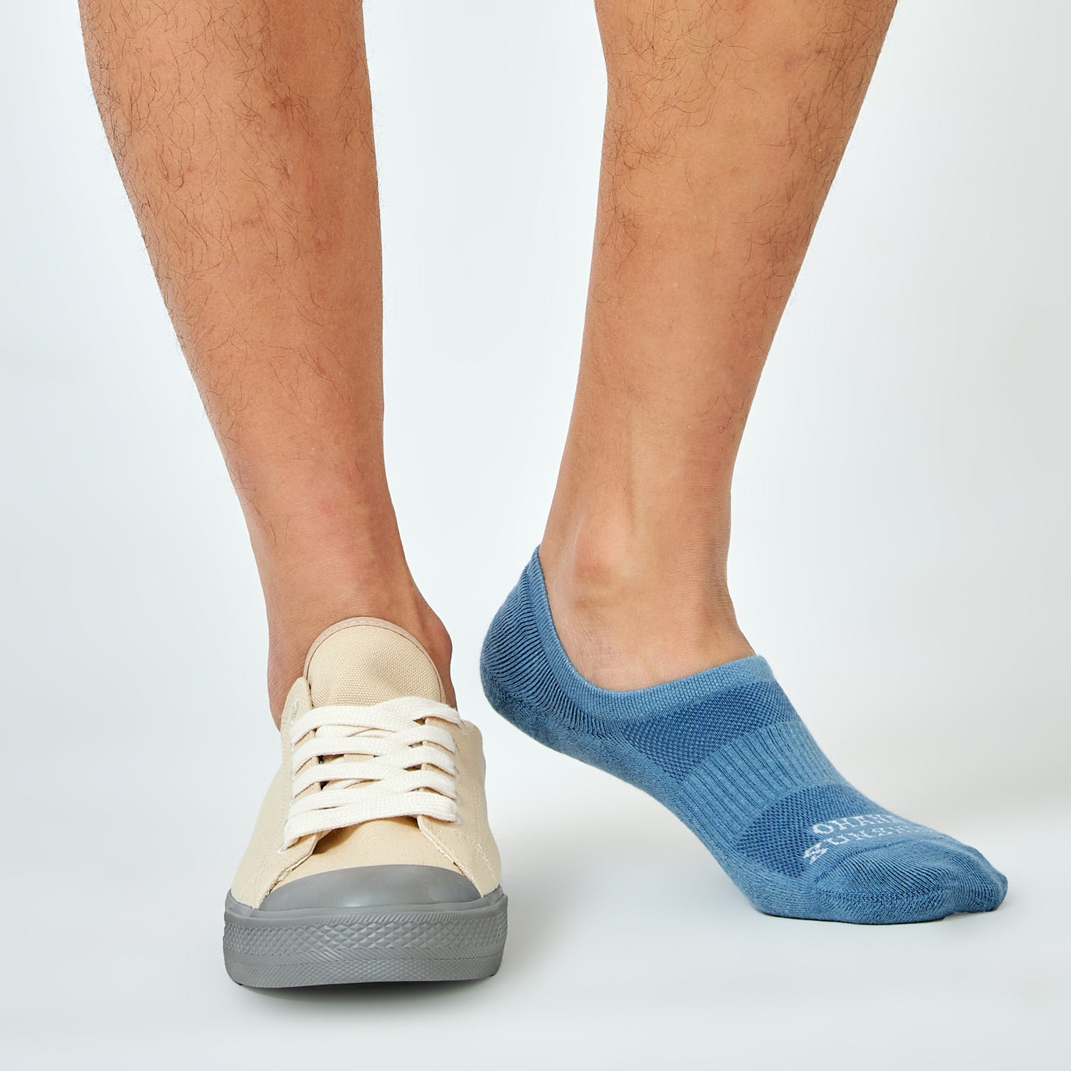 Man wearing one no-show sock and one sneaker, demonstrating invisible fit inside the shoe and antimicrobial sock design for fresh, dry comfort
