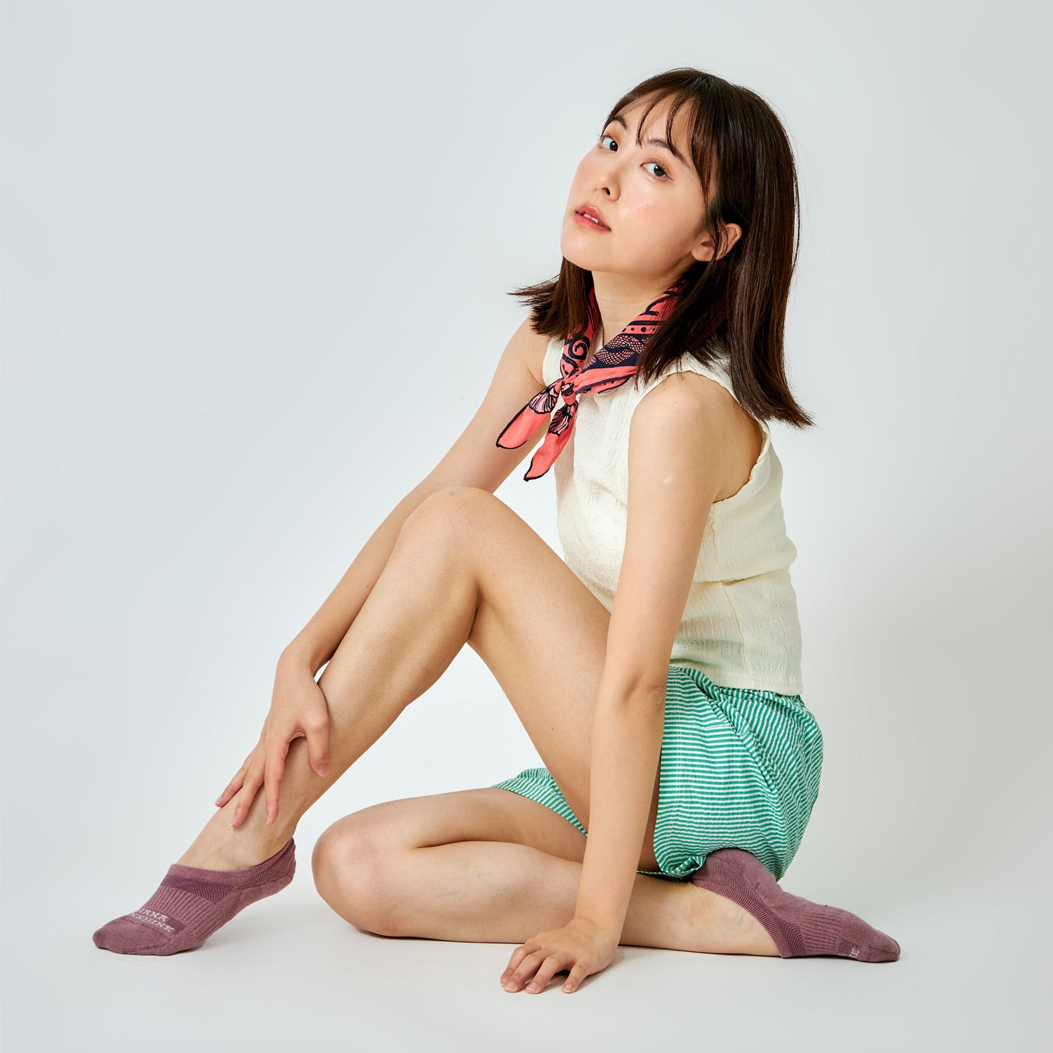 Model seated on floor wearing purple-colored no-show socks by Ohana Sunshine in a relaxed lifestyle look